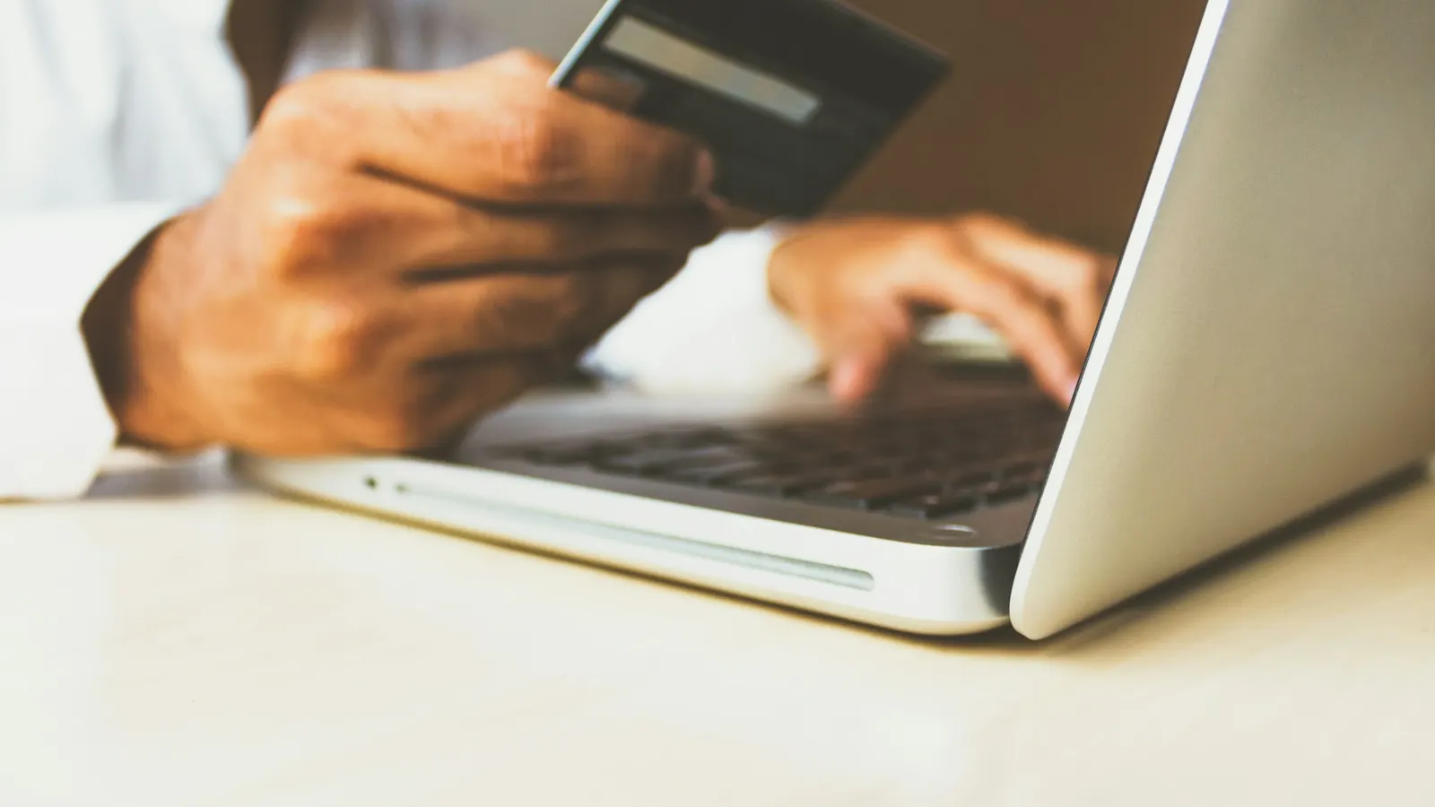 Customer entering credit card details on a laptop to buy from an online gun store