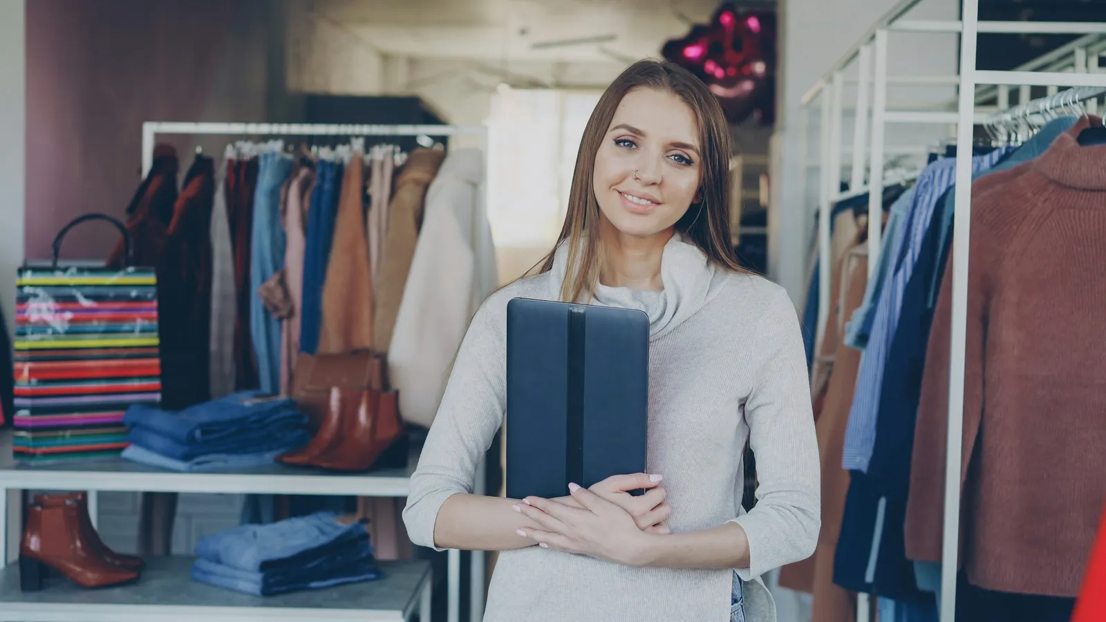 Smiling shop owner holding a tablet in a clothing boutique