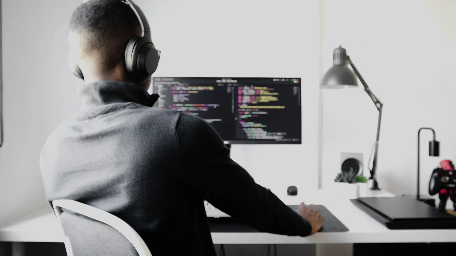 Developer wearing headphones writing code at a desk monitor