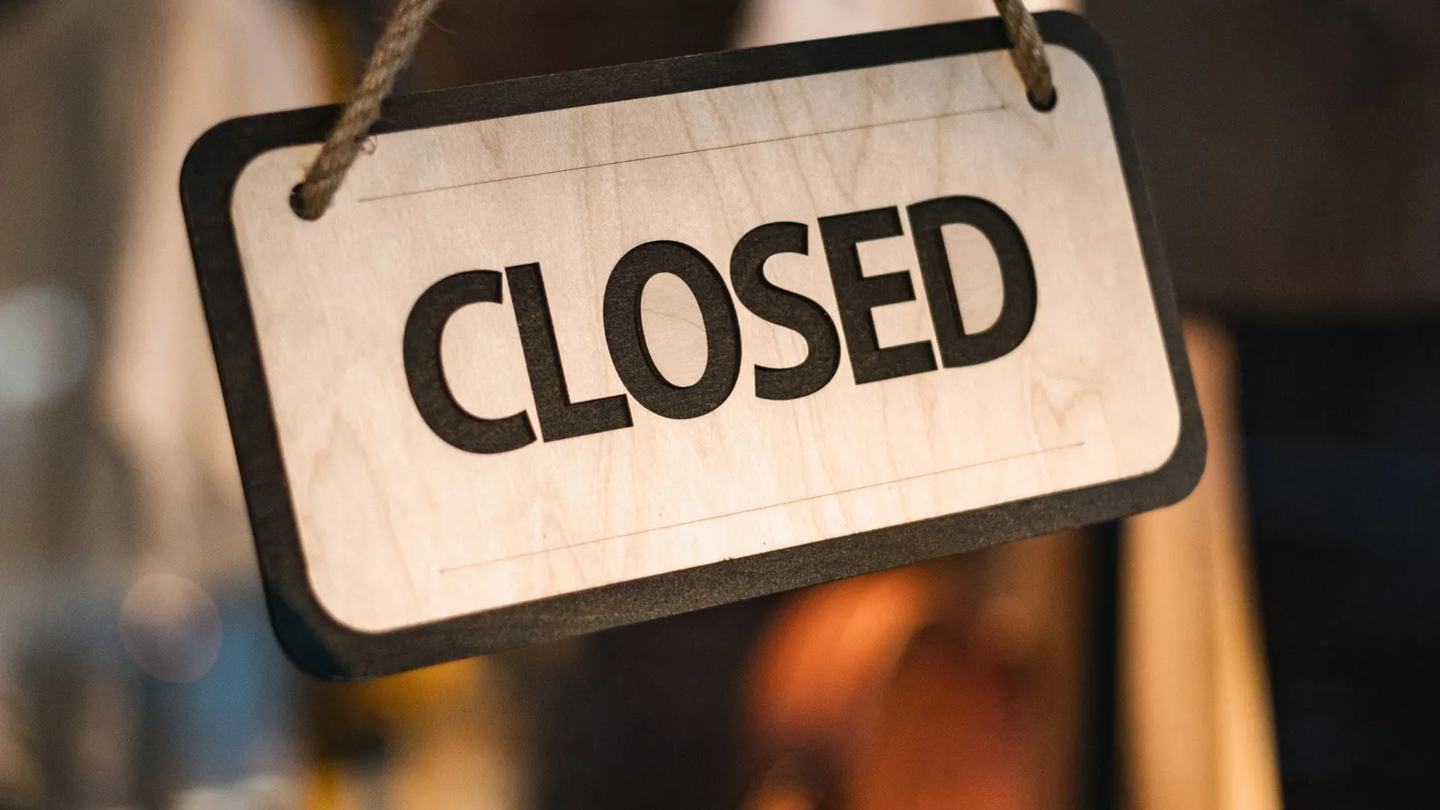 Wooden sign reading Closed hanging from a rope