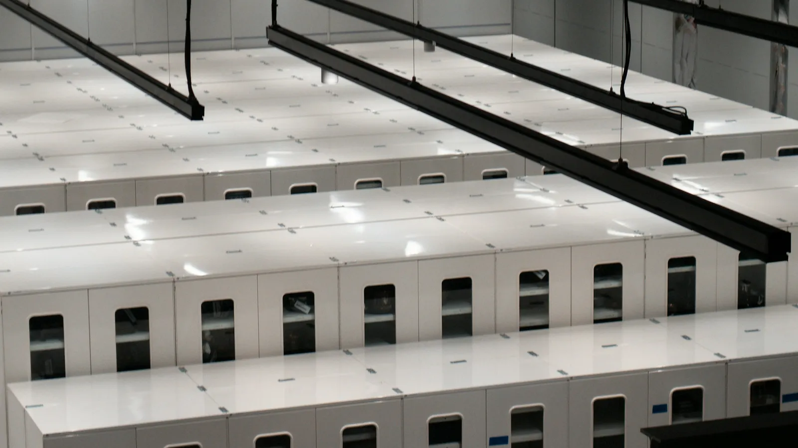 Rows of white server cabinets in a large data center, seen from above