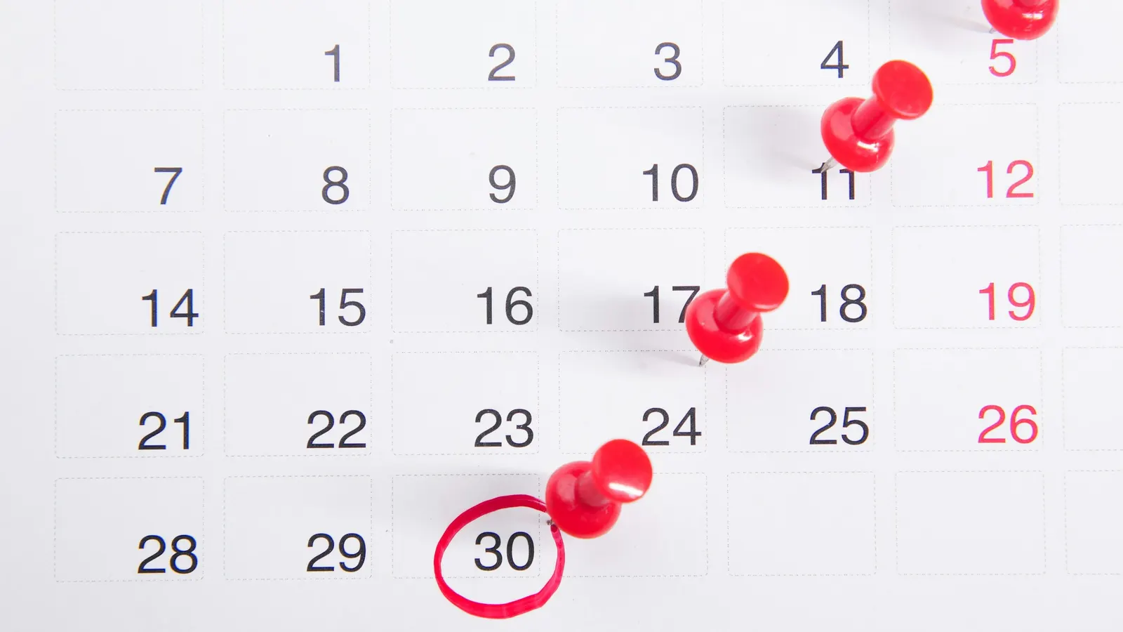Calendar page with red push pins on several dates and the 30th circled in red