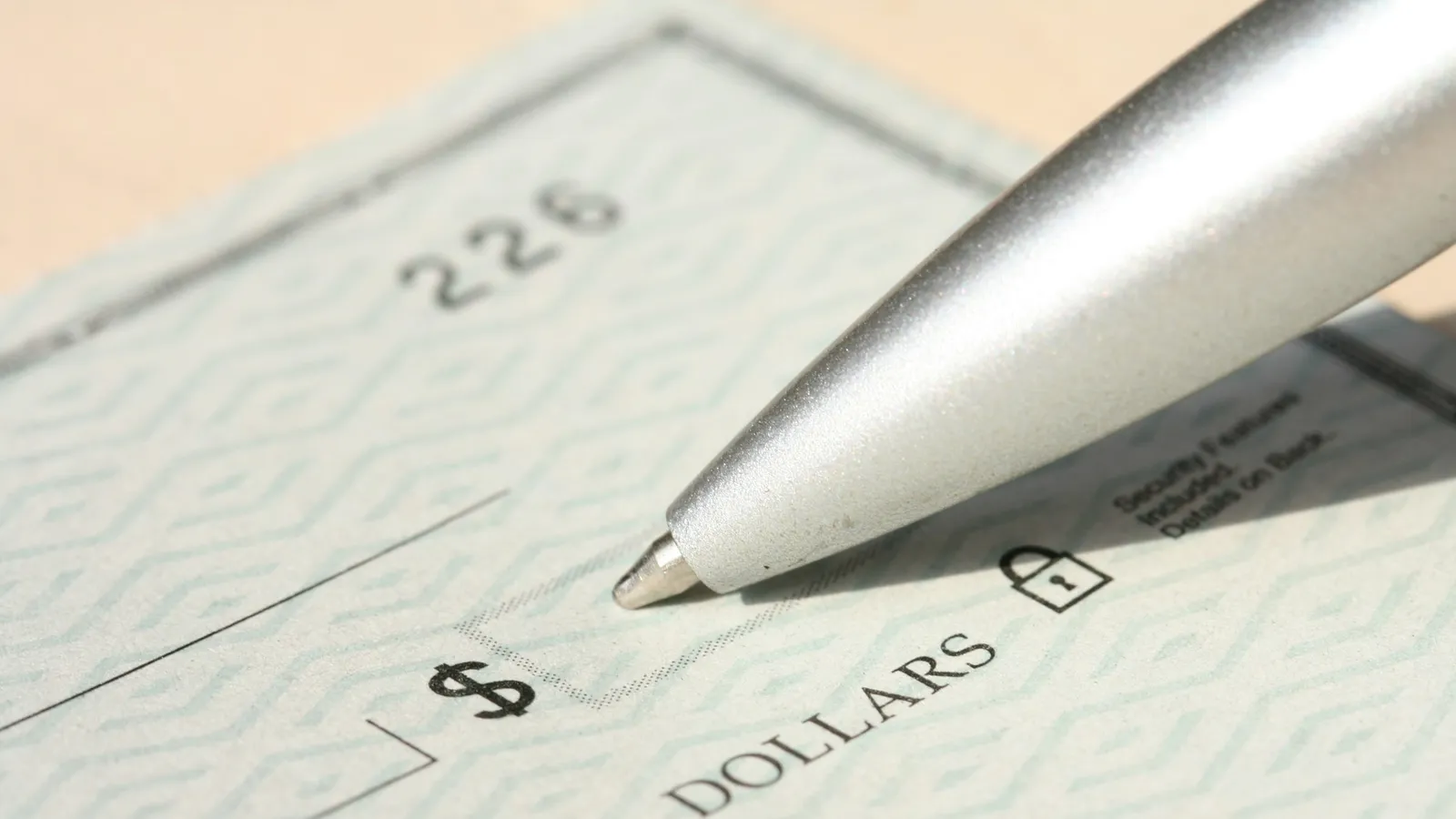 Pen resting on a blank paper check near the dollar amount line