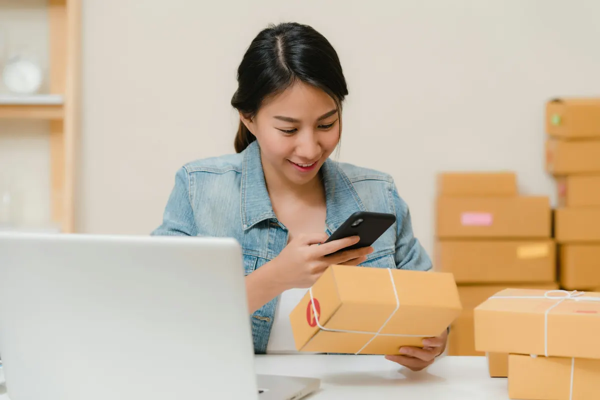 Online store owner preparing orders for shipment next to a laptop
