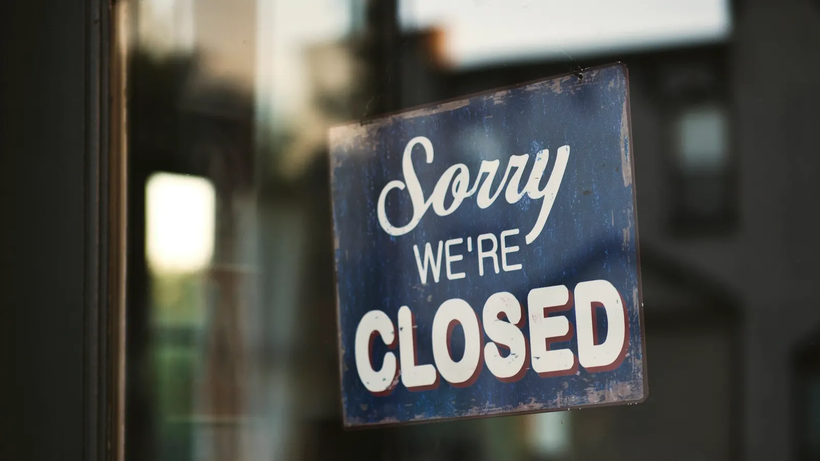 A closed sign hanging in a shop window, like a firearm business that has lost its credit card processing