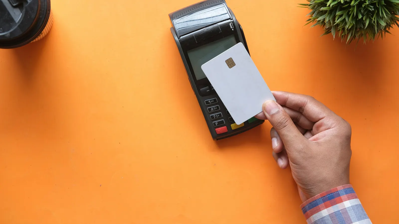 Customer holding a credit card to a payment terminal at checkout