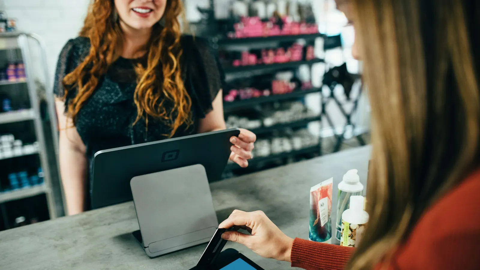 Customer paying at a retail checkout counter with a card reader and tablet POS system