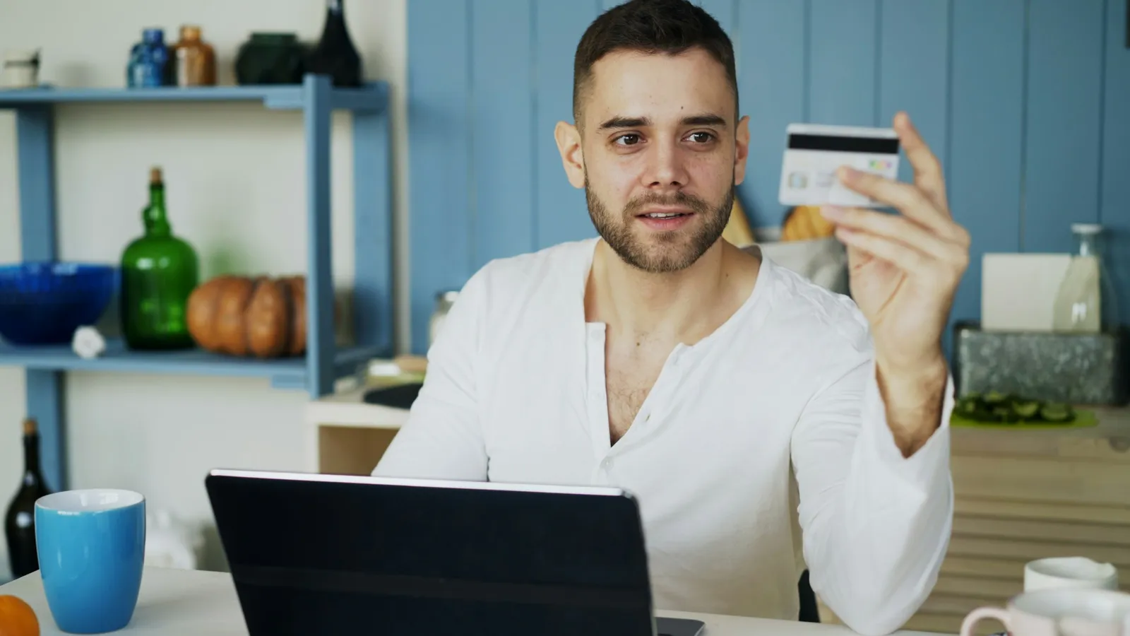 Man at a laptop holding up a credit card
