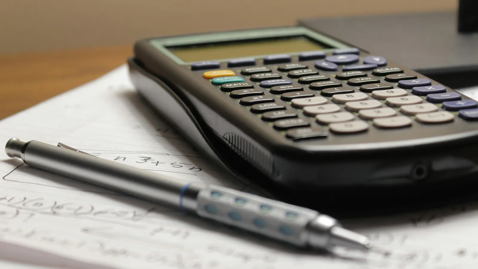 Calculator and mechanical pencil resting on a sheet of handwritten notes