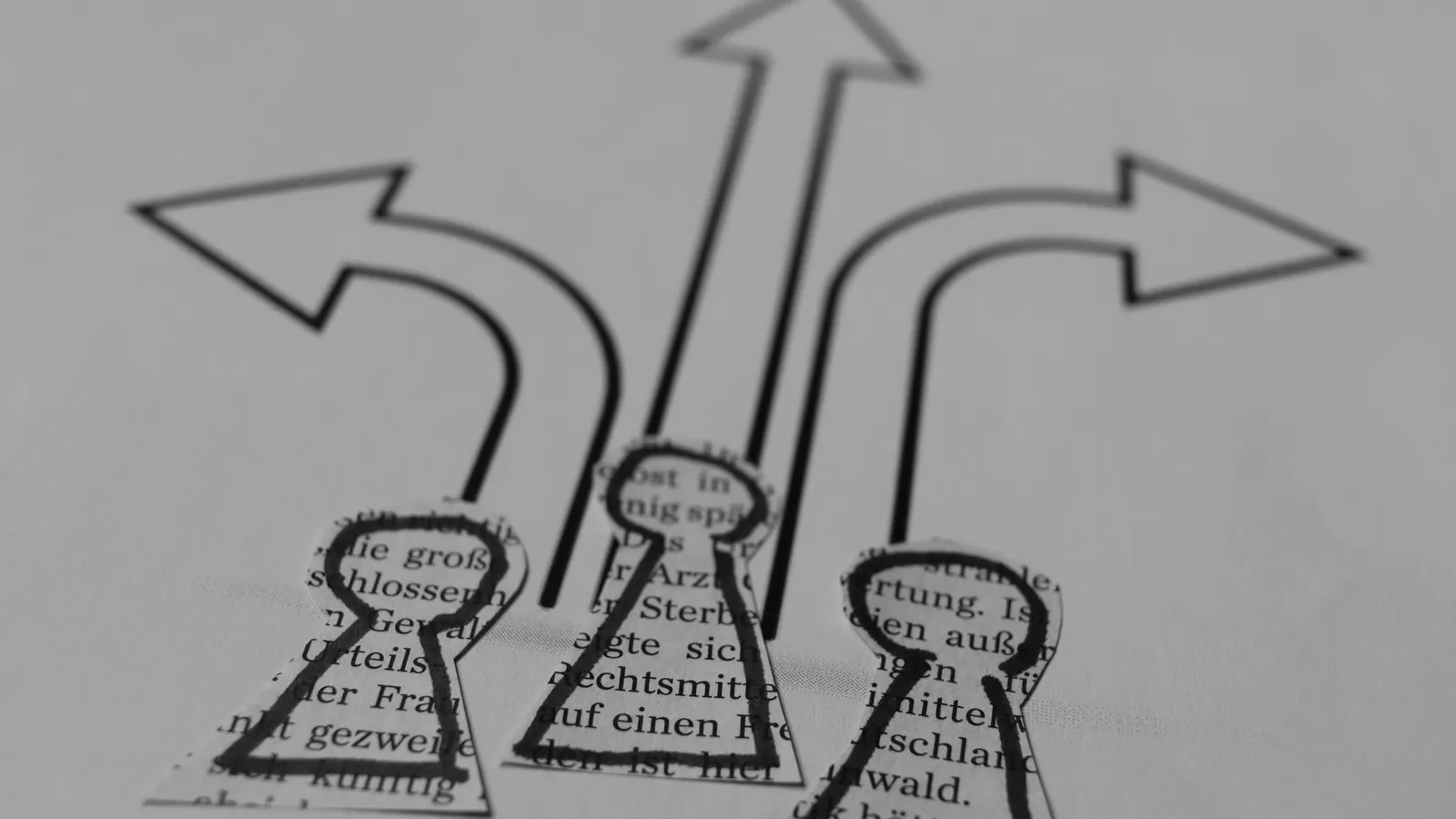 Three hand-drawn arrows pointing left, straight ahead and right on paper