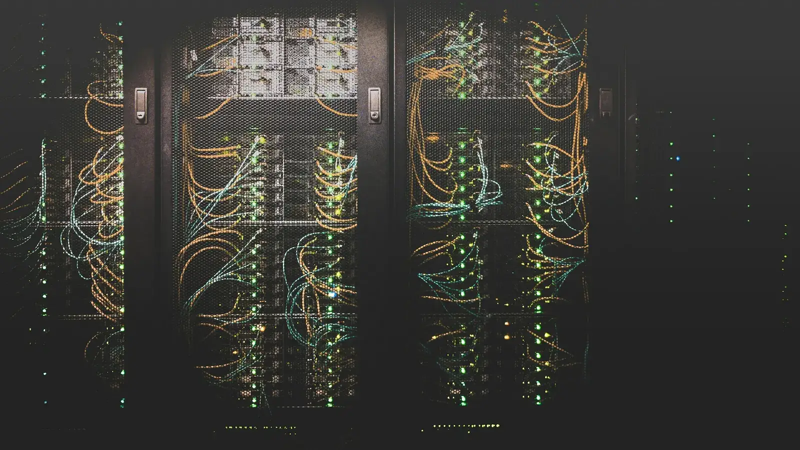 Server racks with bundles of network cables and green status lights